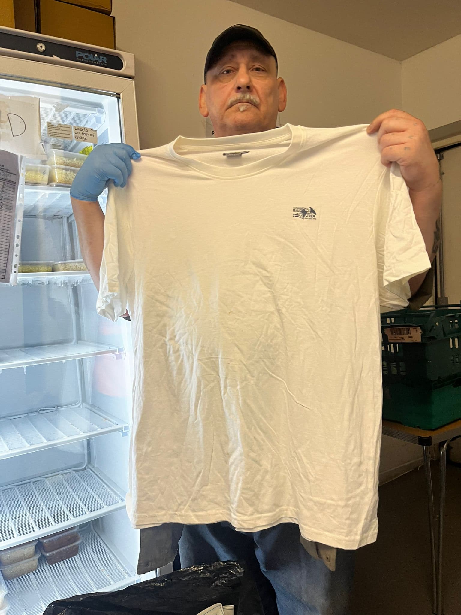 February 2026 Clothing Distribution - Volunteer showing t-shirt distribution