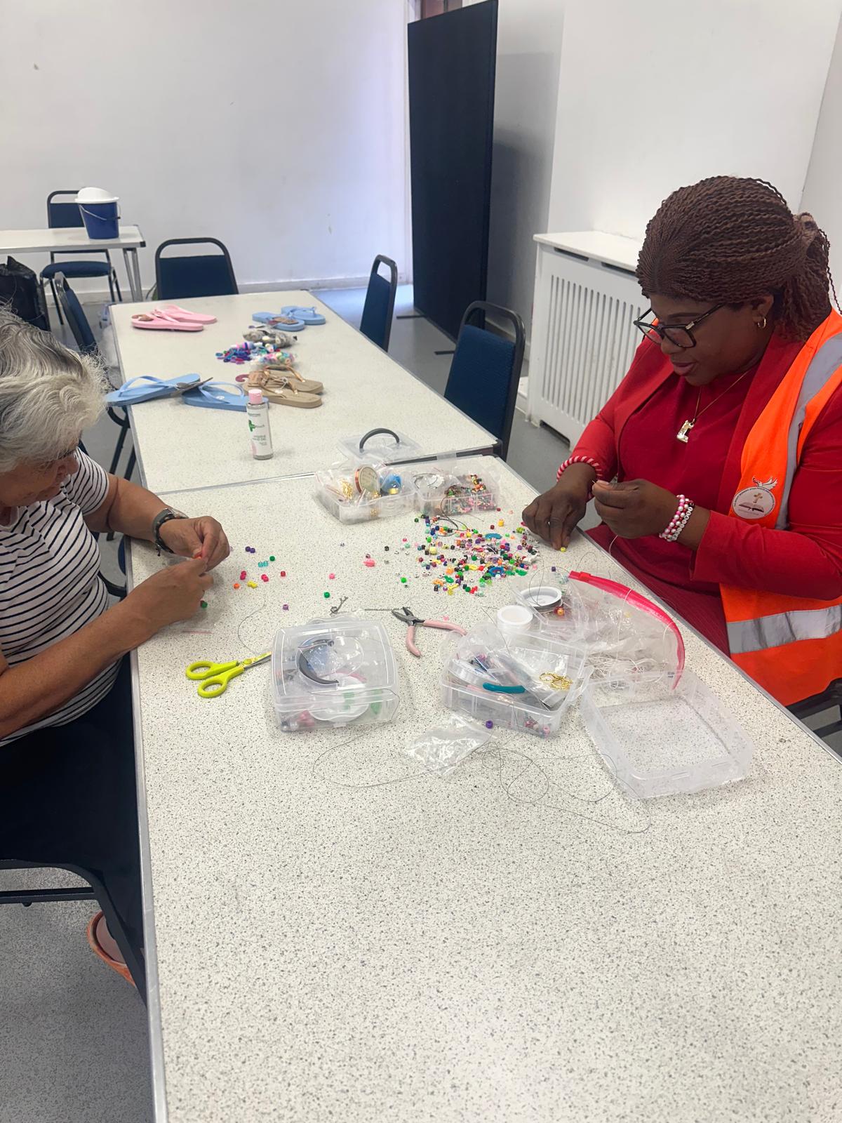 Close-up view of participants working on beading projects with colorful materials spread across the table