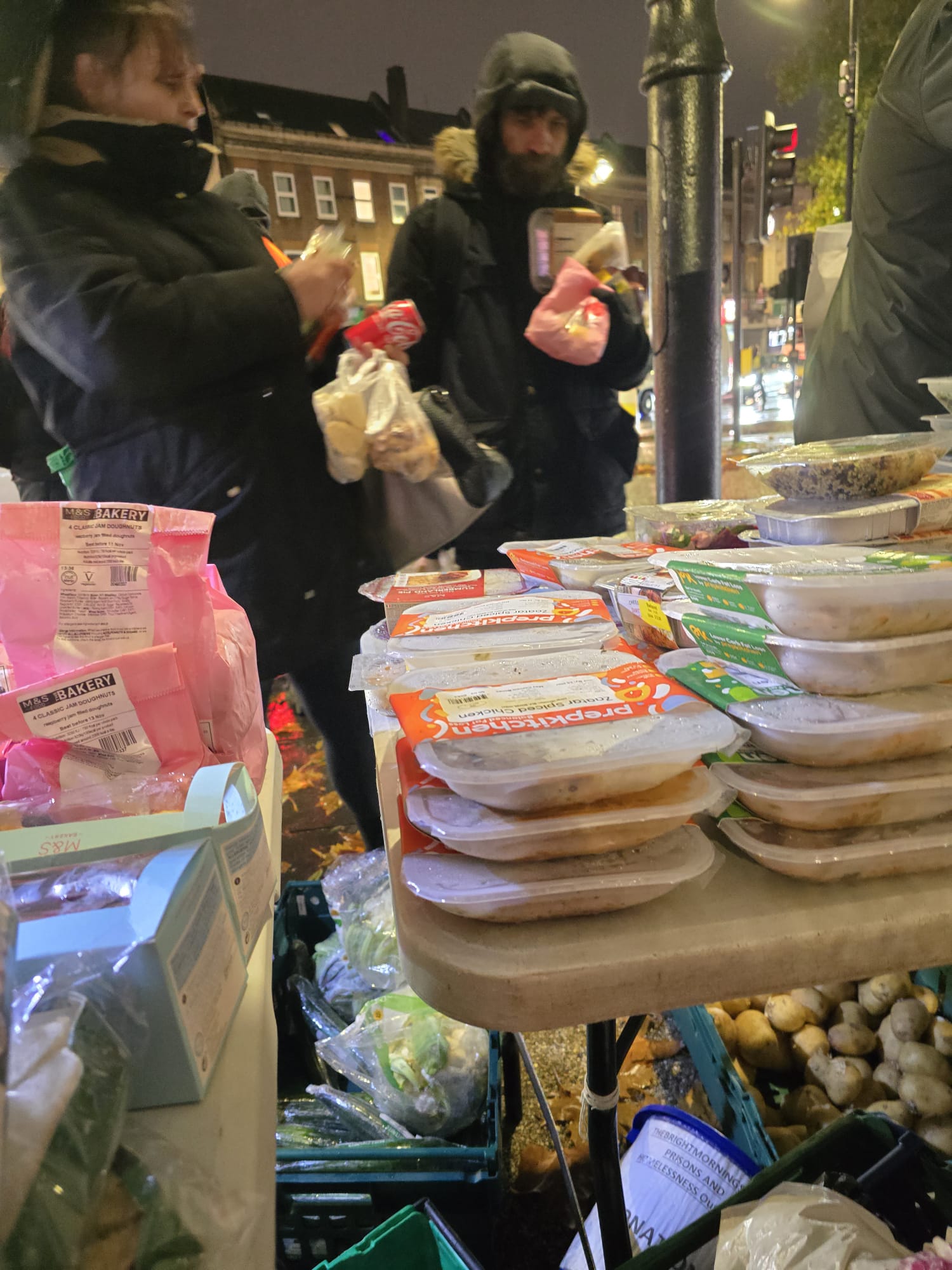 Volunteers and community members gathering at the street food distribution table