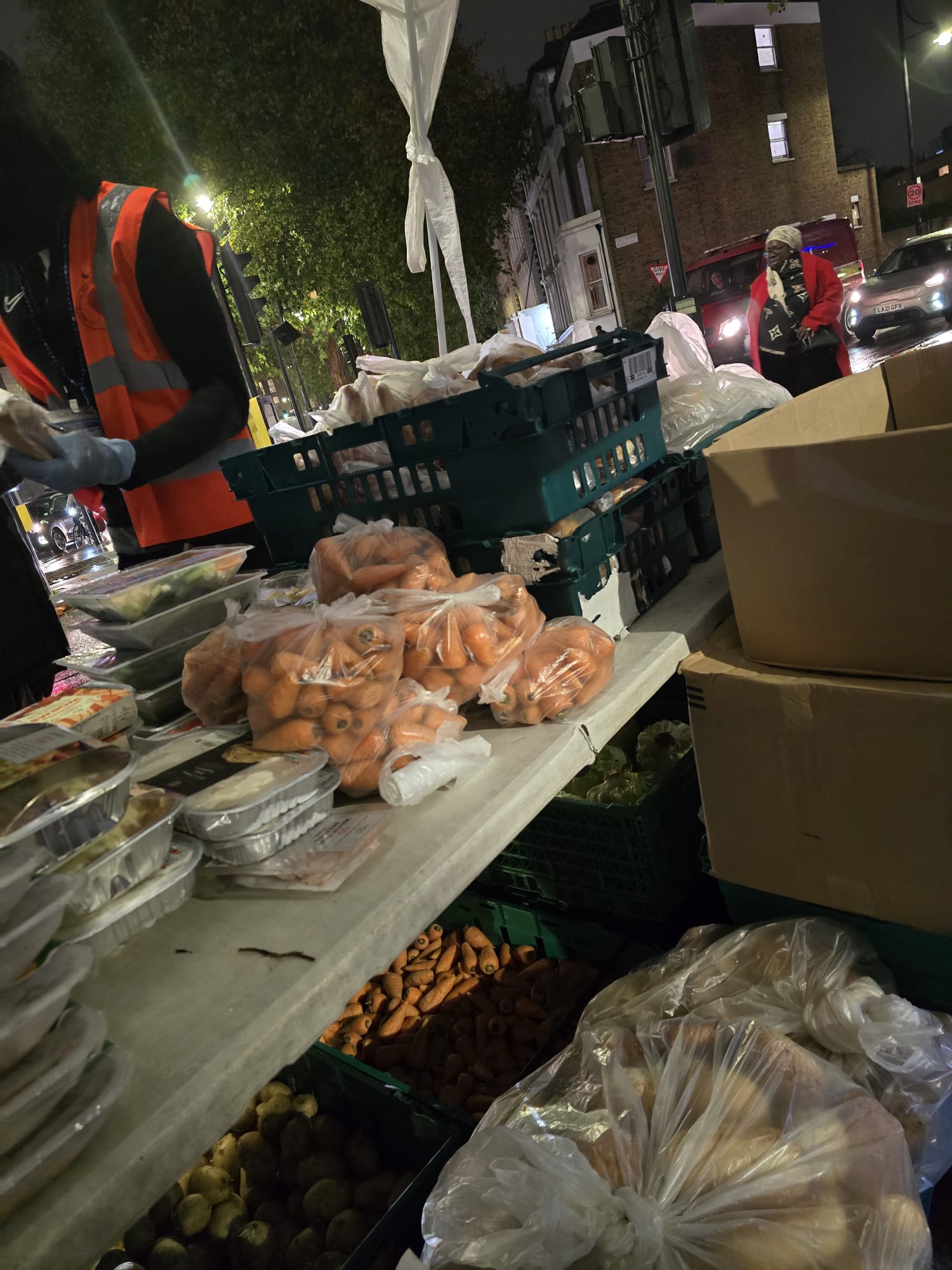 Night-time food distribution with volunteers serving produce and meals